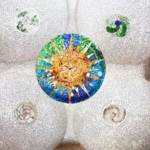 Ceiling mosaic with colorful circular sunburst pattern and spiral designs on a white tiled background, flanked by architectural details.